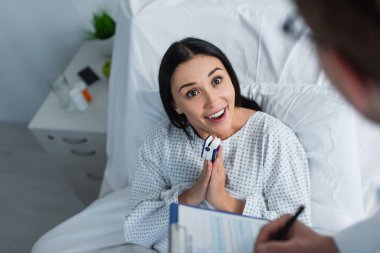 high angle view of smiling woman with praying hands talking with blurred doctor clipart