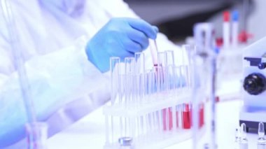 Laboratuvarda kan ve test tüpleriyle çalışan bilim adamının kırpılmış görüntüsü. 