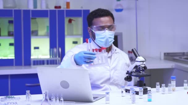 Indischer Wissenschaftler Mit Brille Hält Reagenzgläser Der Nähe Von Laptop — Stockvideo