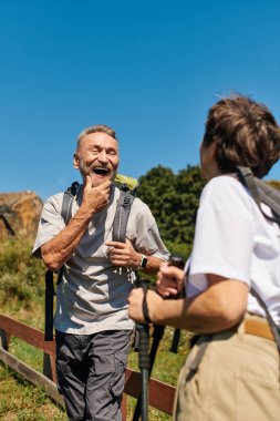 Aktif çift, güzel dağ manzarasında yürürken kahkahalarını paylaşıyor..