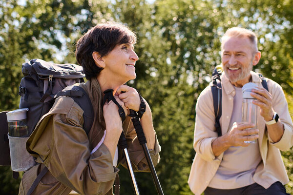 Senior couple enjoys nature together, hiking through beautiful mountainous trails with joy.