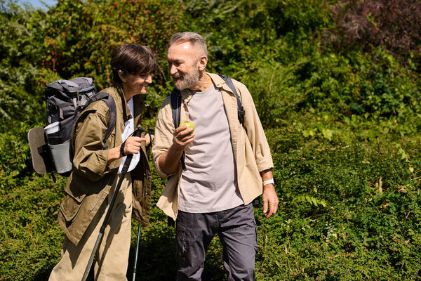 Senior couple explores nature on a hiking adventure while sharing smiles and laughter.