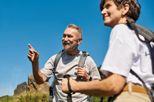 Активные пенсионеры исследуют потрясающие горные тропы вместе, делясь радостными моментами на открытом воздухе.