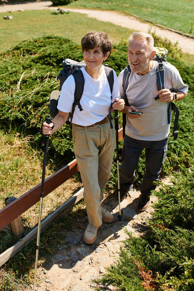 Активная пожилая пара исследует горы, наслаждаясь природой, путешествуя бок о бок.