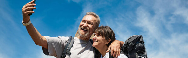 Активная старшая пара наслаждается прекрасным походом, захватывая вместе воспоминания на открытом воздухе, баннер