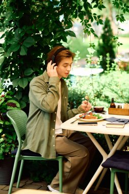 Young man in an olive green shirt savoring his meal while seated in a stylish cafe.