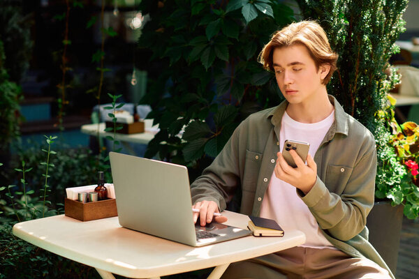 Young man in a shirt focuses on his laptop while seated in a cafe, enjoying the ambiance.
