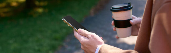 Young man in a fashionable coat sipping coffee and texting, banner