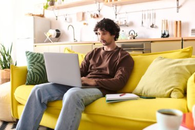 Handsome young man works intently on his laptop in a stylish and inviting space.