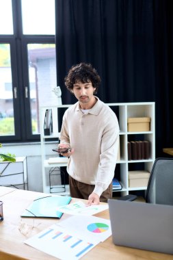 Handsome young man analyzes data and discusses reports while working in a sleek office setting.