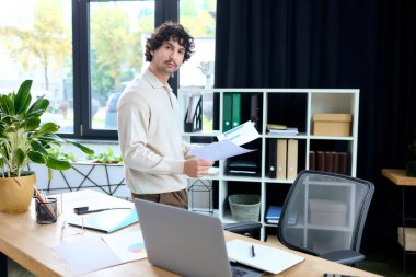 Young man in a stylish office, engaged in work while holding important papers in his hands.