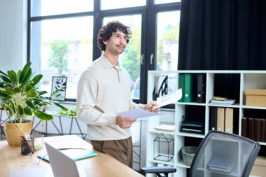 Confident young professional enjoys a moment in a stylish office, engaged with paperwork.