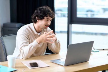 A young man actively participates in a virtual meeting, showcasing his focus and professionalism.