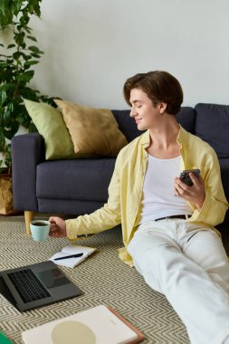 Modaya uygun bir genç adam yeşil, şık bir oturma odasında kahve ile yerde dinleniyor..