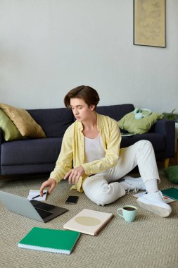 Dizüstü bilgisayarında şık bir adam yazıyor. Etrafı defterlerle çevrili ve rahat bir yerde kahve içiyor..