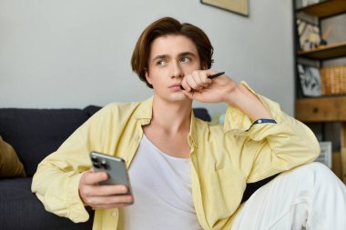 Şık bir genç adam evinde oturmuş, elinde akıllı bir telefonla derin düşüncelere dalmış..