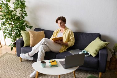 Genç ve yakışıklı bir adam kanepeye rahatça oturur ve yakınlarda bir kahve fincanı ile deftere bir şeyler yazar..