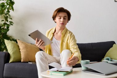 Kanepede oturan, elinde tablet, elinde kahveyle notlar yazan şık bir genç adam..