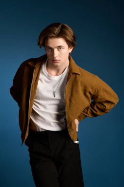 Kendine güveni olan genç, modaya uygun bir adam stüdyo ortamında moda giysileri sergiliyor..