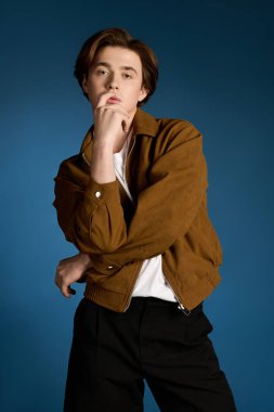 Yakışıklı genç adam içeride yaratıcı bir şekilde poz verirken şık kıyafetlerini sergiliyor..