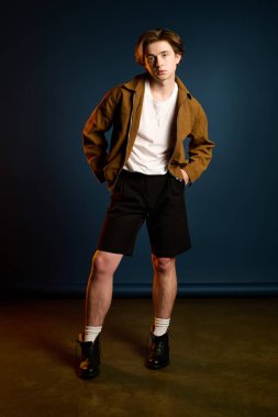 Şık genç adam gururla duruyor, yaratıcı bir ortamda modern tarzını sergiliyor..