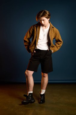 Genç ve yakışıklı bir adam kendine güvenerek duruyor, şık kıyafetini cazibesi ve tarzıyla sergiliyor..