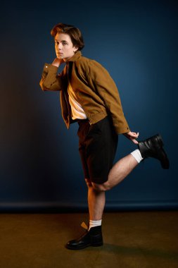 Yakışıklı genç bir adam, stüdyoda eğlenceli bir poz verirken modaya ayak uyduruyor..