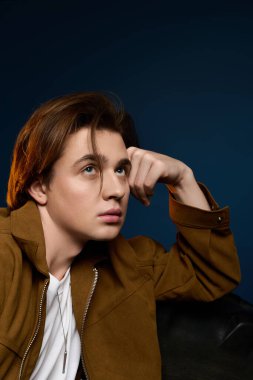 Yakışıklı, şık saçlı ve kahverengi ceketli bir adam yaratıcı bir çevrede derin düşünür..