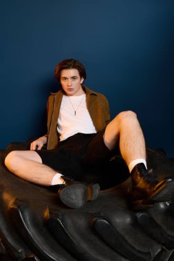 Tarz sahibi genç bir adam kendine güvenini ve modern modasını gösteren eşsiz bir yapıda gelişigüzel poz verir..