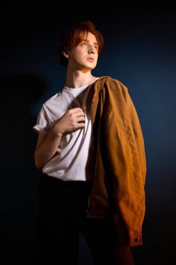 Kahverengi ceketli, modern moda saçan bir genç poz verdi..