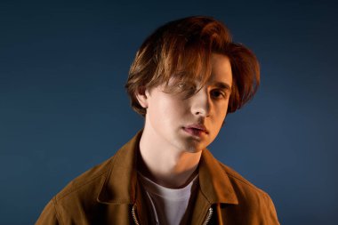 Yakışıklı genç adam kendine güvenerek duruyor, şık görünüşünü ve rahat tavırlarını sergiliyor..