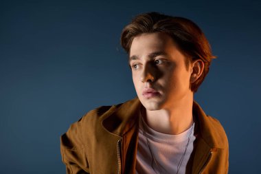 Genç adam moda tarzını sergiliyor, düşünceli bir şekilde bakıyor, kendine güvenini ve çekiciliğini sergiliyor..