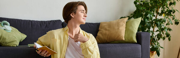 Стильный молодой человек расслабляется с блокнотом, отражаясь в ярком и уютном пространстве.