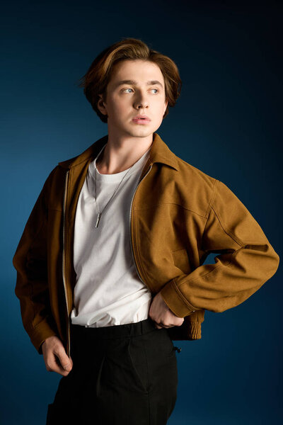 A stylish young man in a brown jacket and white shirt showcases modern fashion.