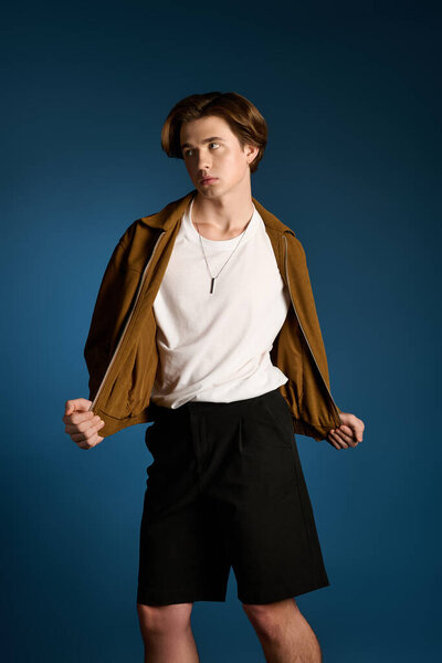 Handsome young man showcases trendy outfit while striking a playful pose in a studio setting.