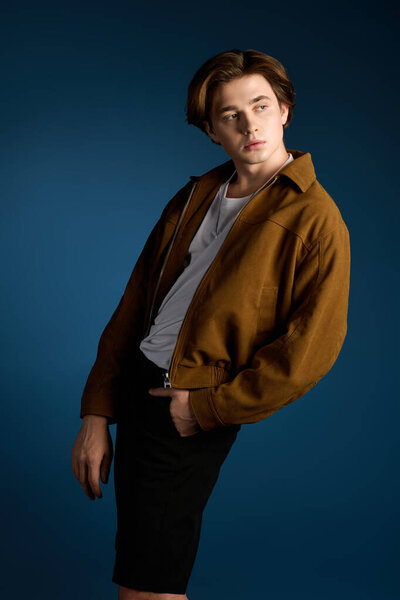 A young handsome man stands confidently, showcasing his trendy outfit and stylish demeanor.