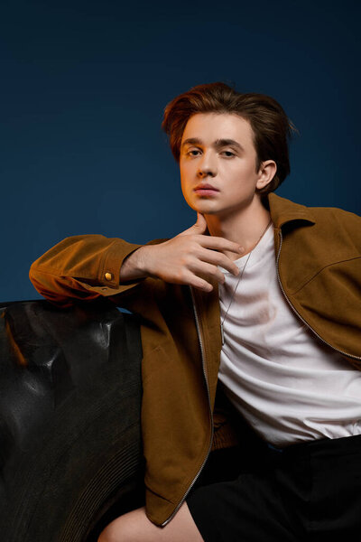 Handsome young man dressed in stylish attire strikes a dynamic pose in a contemporary space.