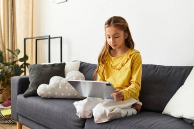 Genç nesil alfa kız kanepede rahatlar, bir tabletle mutlu mesut meşgul olur, ilgi alanlarını keşfeder..