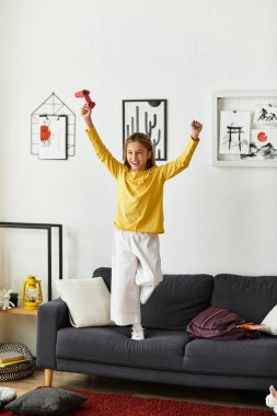 Bir kız evinde vakit geçirir, video oyunları oynar ve zaferini neşeyle kutlar..