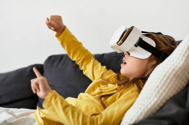 Sarı elbiseli bir kız evde kanepede dinlenirken sanal gerçeklikten zevk alır..