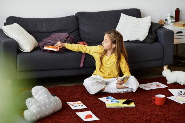 Mutlu bir kız çizimleriyle çevrili kırmızı halıda sanat yaratıyor..