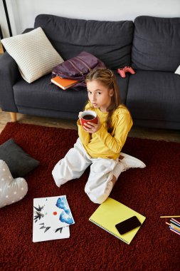 Genç bir kız sıcak bir içkiyi yudumlarken evde rahat bir öğleden sonranın tadını çıkarıyor..