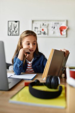 Etrafı çalışma materyalleriyle çevriliyken bir kitabın içine dalmış bir alfa kızı..