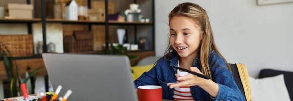 Bright and cheerful girl interacts with her laptop while enjoying a cup of her favorite drink, banner