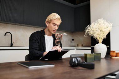 Şık bir genç adam telefonda konuşurken çağdaş bir dairede düşünceli bir şekilde çalışır..