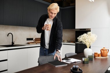 Yakışıklı genç adam modern bir mutfakta içki servisi yaparken gülümsüyor, odaklanmış ve yaratıcı..