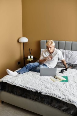 Yakışıklı adam dizüstü bilgisayarı üzerinde çalışırken şık dairesinde rahatlıyor..