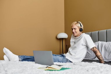 Yakışıklı bir genç adam kulaklıkla müzik dinliyor, şık bir dairede rahatça gülümsüyor..