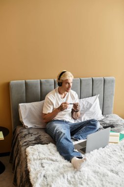 Genç bir adam, modern bir dairede rahatça otururken dizüstü bilgisayarında oyun oynamaktan hoşlanır..