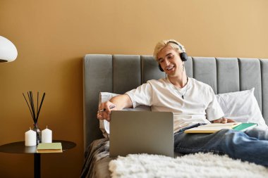 Genç adam rahat bir dairede dinleniyor, müziğe dalmış ve bir deftere yazıyor..